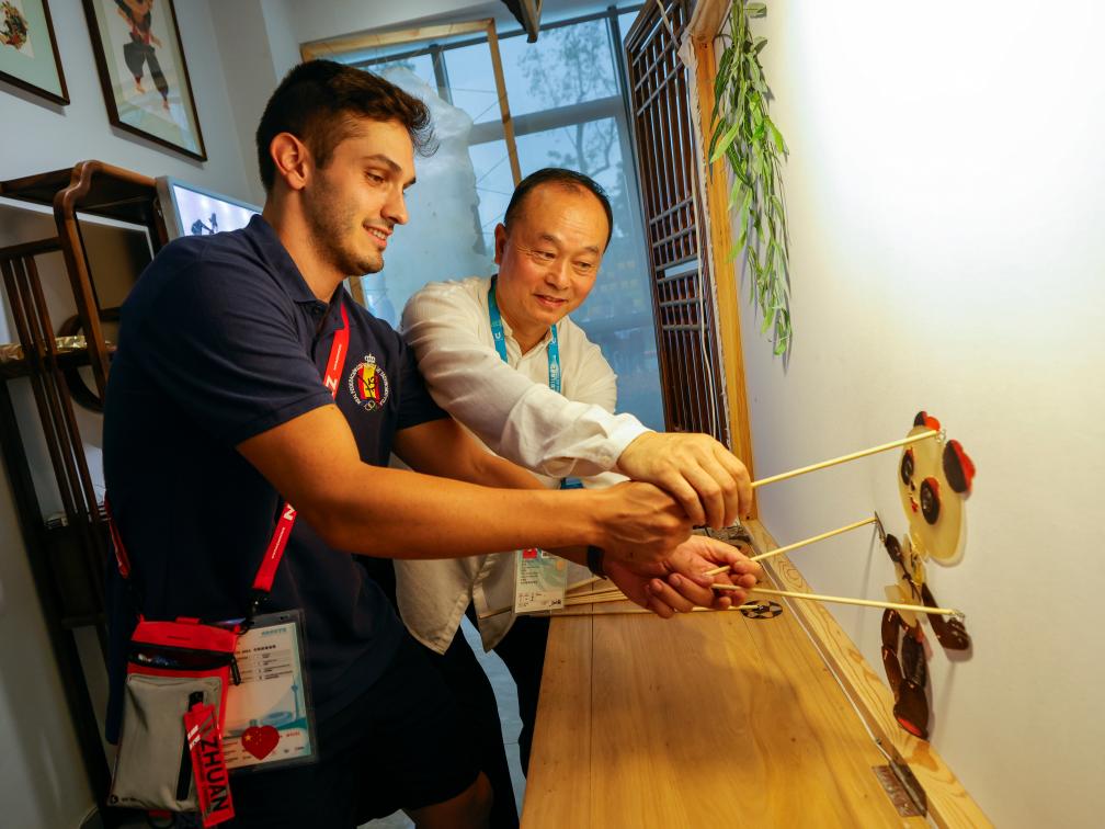 8月2日，在成都大運村的互動體驗中心，西班牙代表團成員胡安·米格爾·戈麥斯·戈麥斯（左）在非遺項目成都皮影戲代表性傳承人趙洪的指導下演皮影戲。新華社記者沈伯韓攝